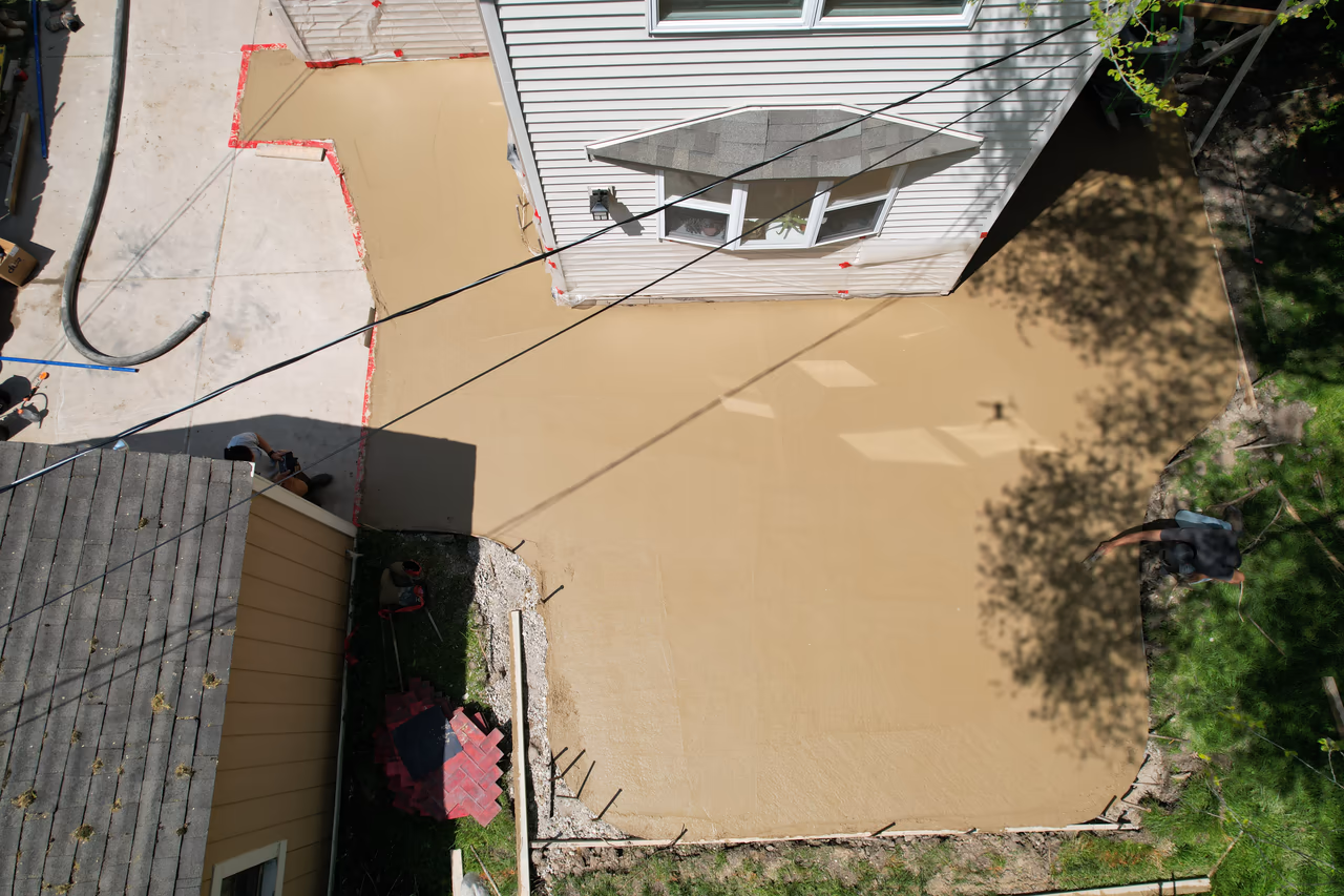Drone overhead shot of wet concrete patio slab with stamping forms staged nearby, Grand Rapids MI