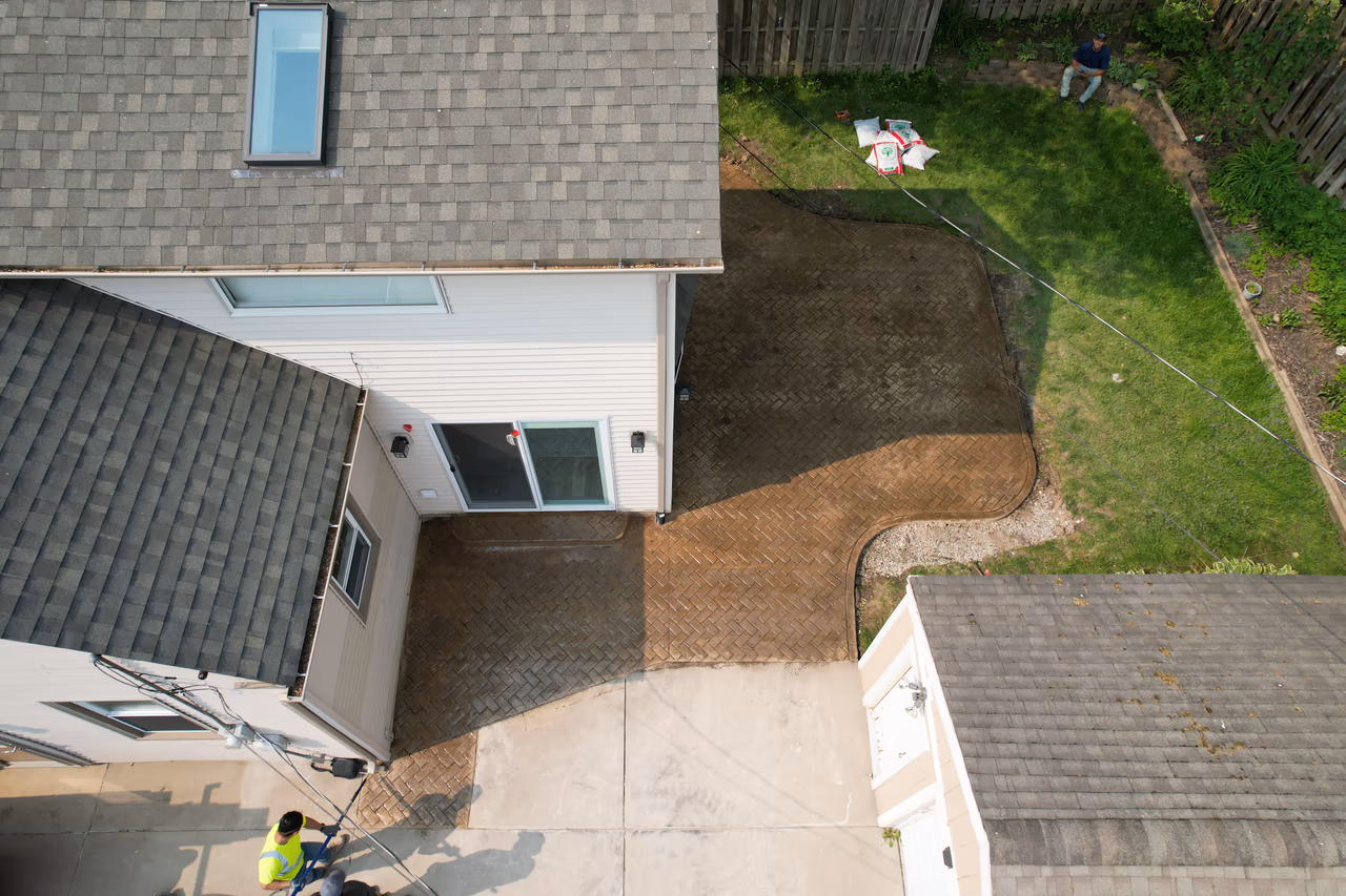 Overhead drone view of completed herringbone stamped concrete patio layout beside home
