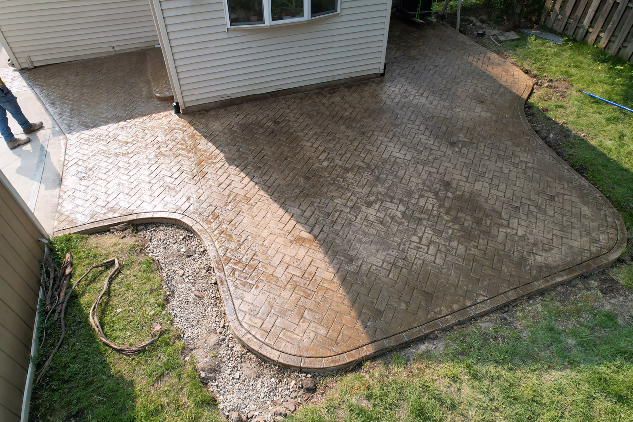 Completed herringbone stamped concrete backyard patio with scalloped border, Grand Rapids MI