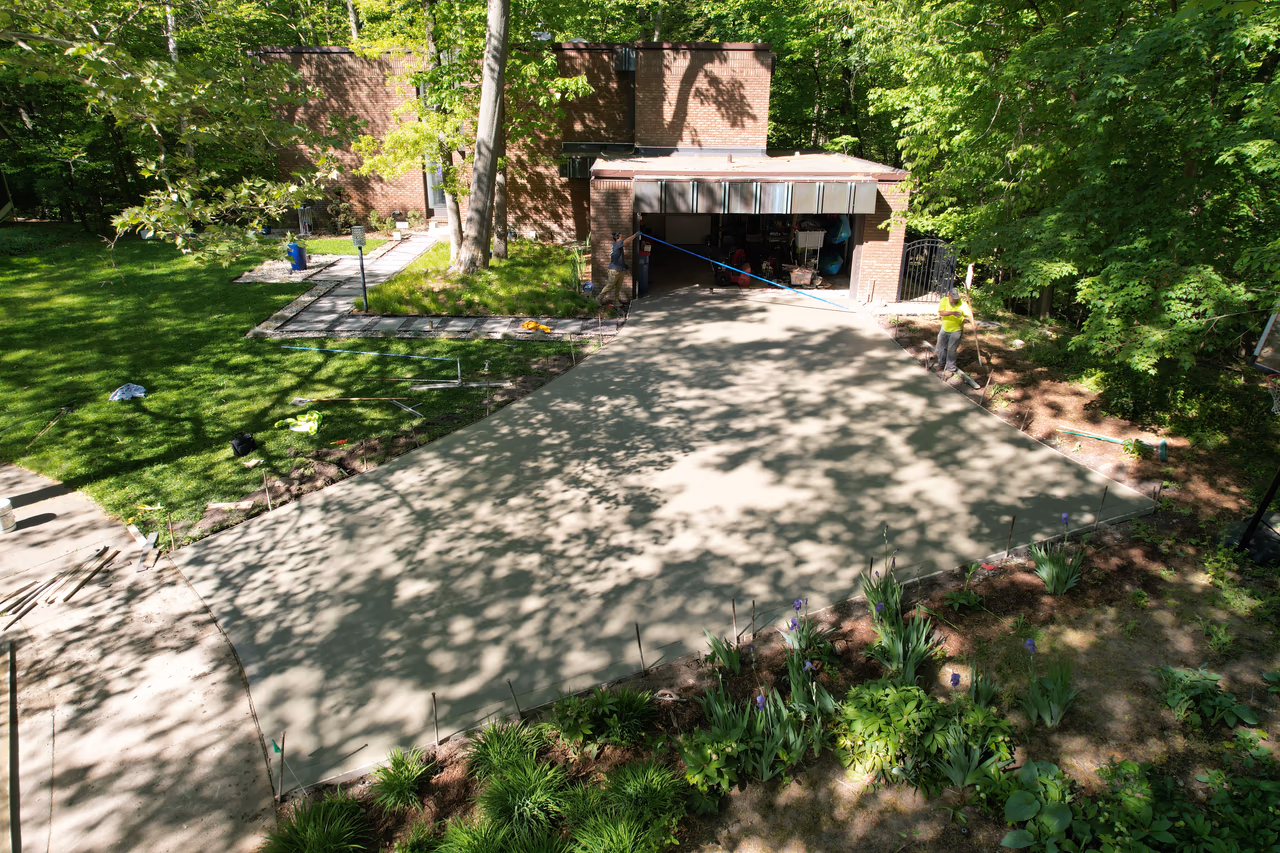 Freshly poured concrete driveway curing next to two-car garage, aerial view Grand Rapids MI
