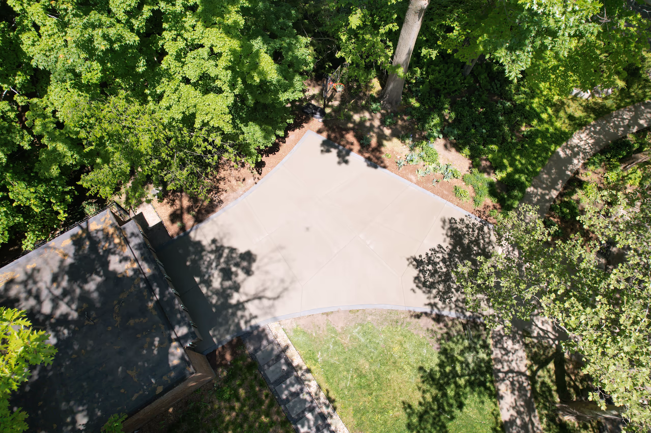 Overhead drone shot of completed modern concrete driveway surrounded by mature trees