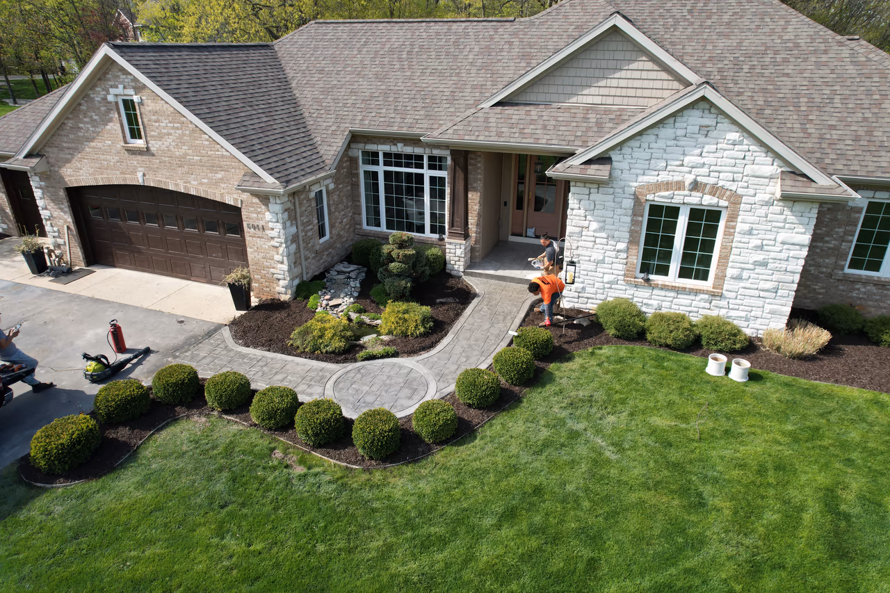 Aerial view of a finished curved stamped concrete walkway complementing front yard landscaping with Pro Concrete Services crew on site in Caledonia MI