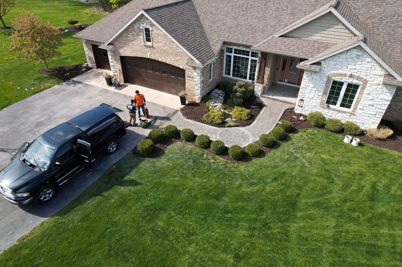Full aerial view of completed curved stamped concrete walkway integrated into front yard landscaping with Pro Concrete Services truck in Caledonia MI