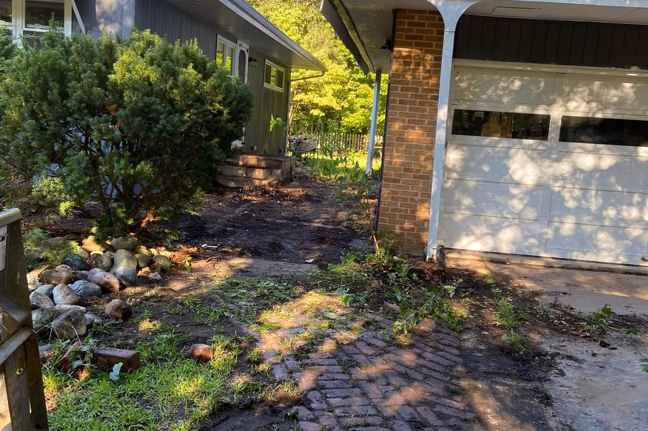 Before photo of overgrown brick walkway and neglected front yard prior to concrete replacement in Grand Rapids MI