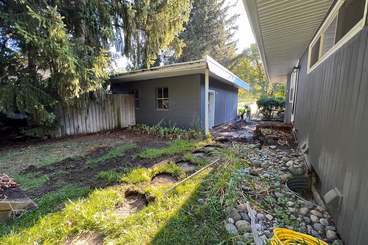 Pro Concrete Services crew excavating rear yard area behind detached garage during concrete overhaul in Grand Rapids MI