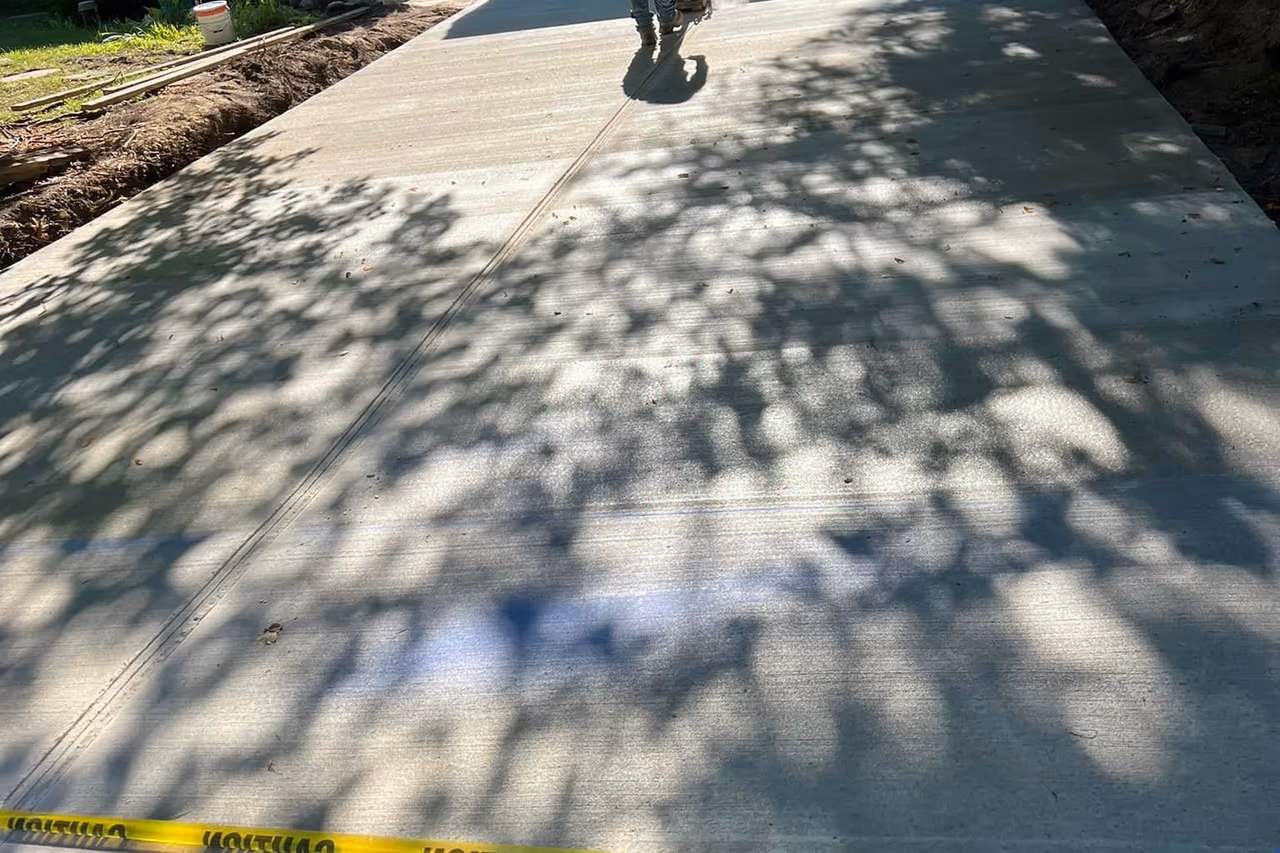 Pro Concrete Services crew applying sealer to new broom finish concrete driveway in Grand Rapids MI