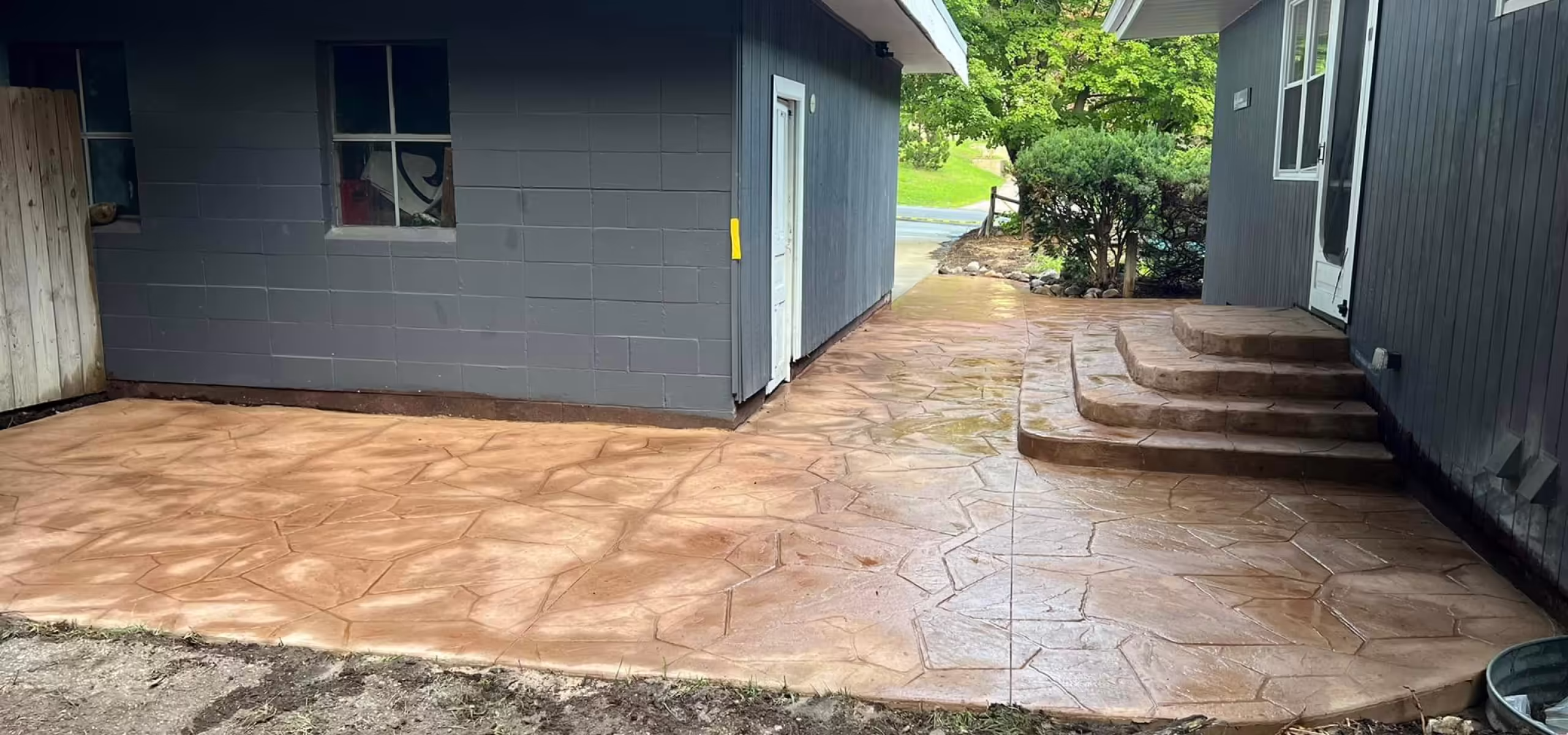 Wide view of completed stamped flagstone concrete surface wrapping around detached garage with steps in Grand Rapids MI