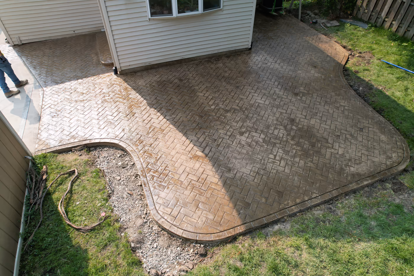 Pro Concrete Services crew applying sealer to freshly stamped herringbone concrete patio, Grand Rapids MI