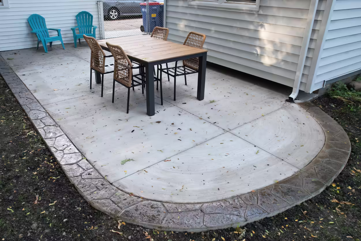 full patio in frame, furniture adds lifestyle context, stamped border readable all the way around, rounded shape clearly visible. Strongest read at both card and hero scale.