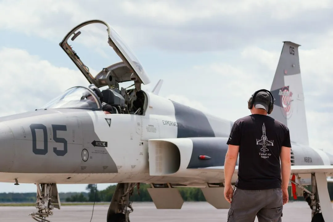 F5 jet on tarmac with cockpit open, mechanic in front