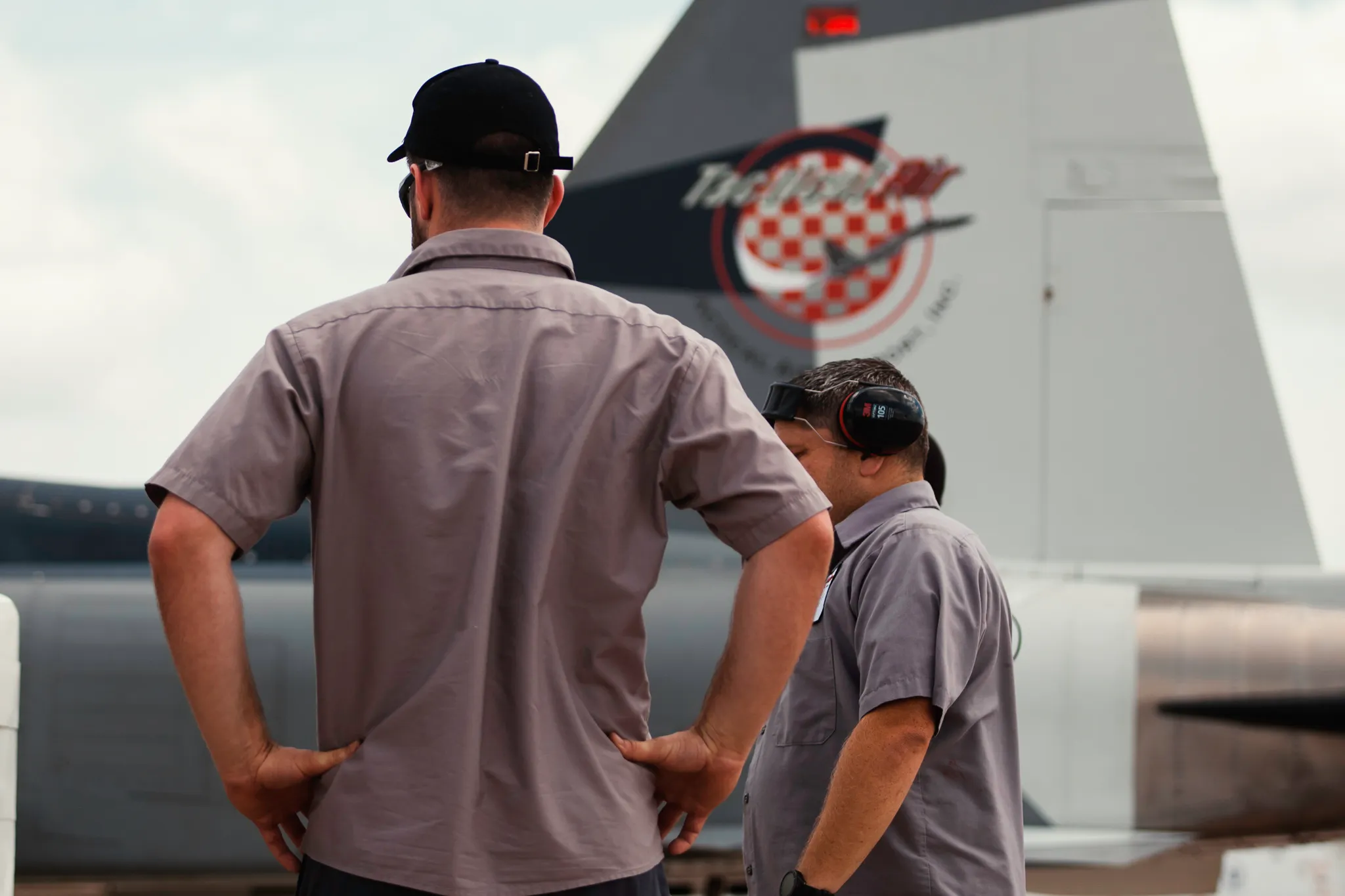Tactical Air Support mechanics standing next to F5 fighter tail facing away