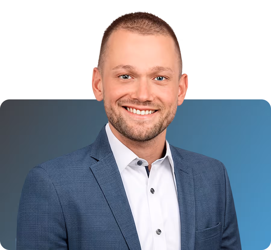 Porträt eines lächelnden Mannes mit kurzem Haar, der einen weißen Hemd und eine blaue Jacke trägt.