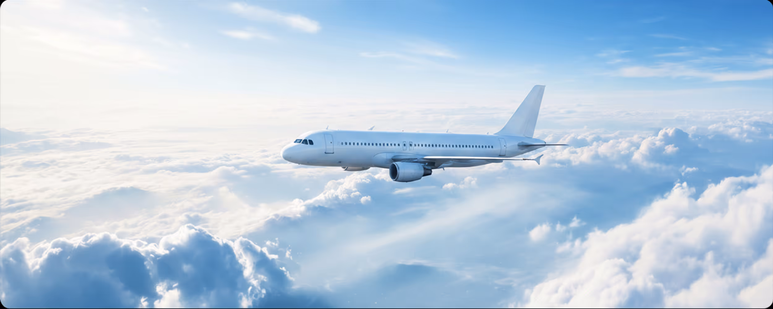 Passagierflugzeug fliegt hoch über weißen Wolken an einem klaren blauen Himmel.