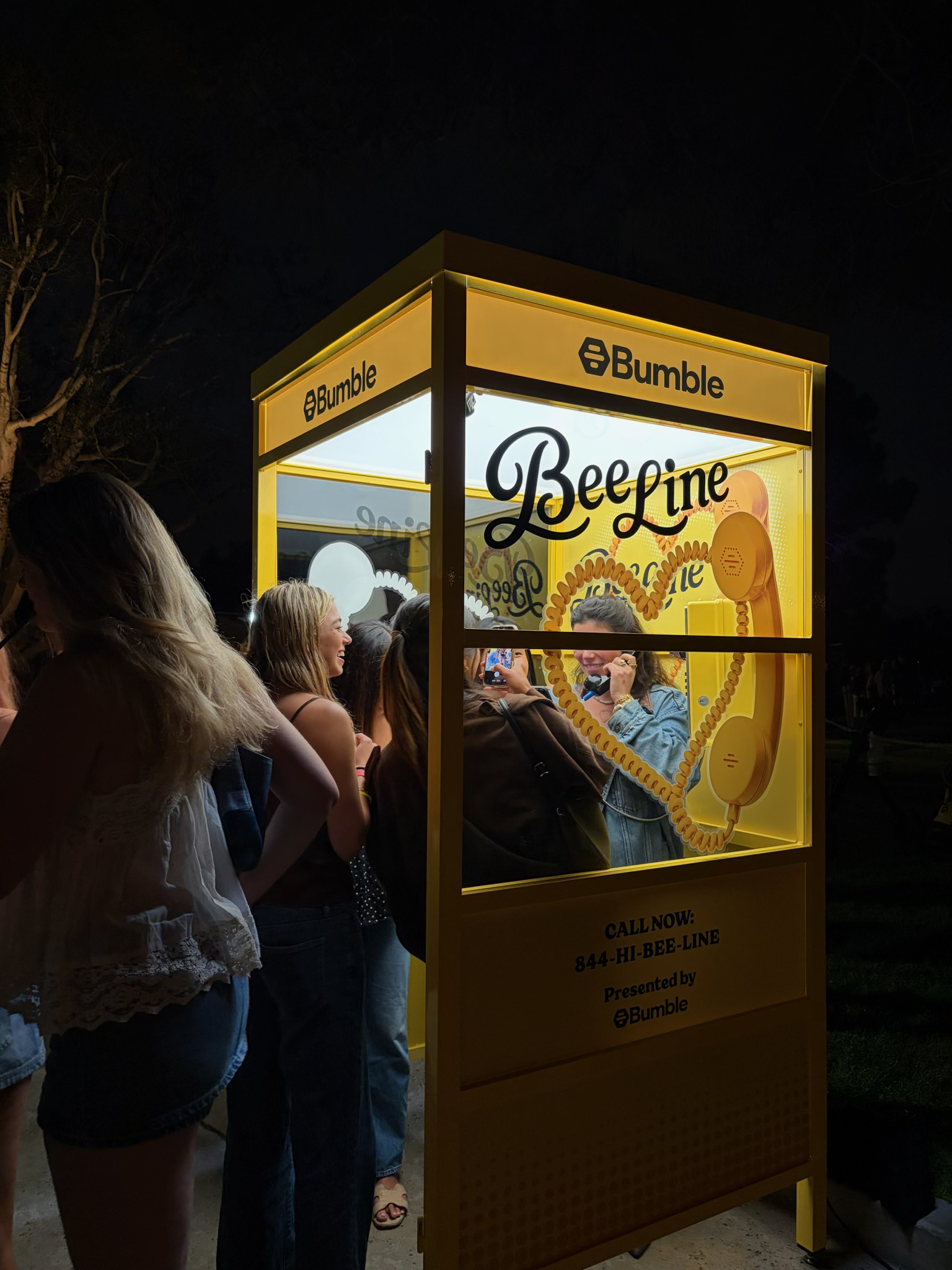 Guests lined up at the Bumble BeeLine phone booth activation at night