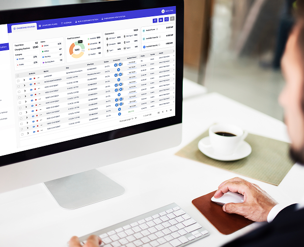 Person using computer displaying a dashboard with charts, data tables, and statistics, with a cup of coffee nearby.