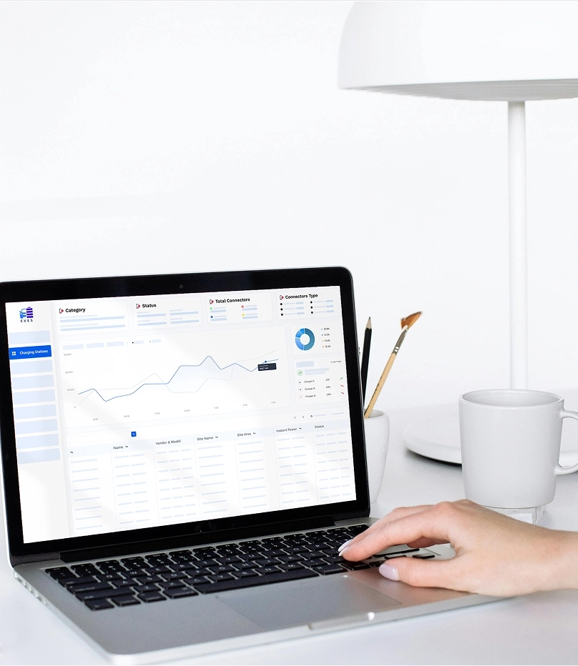 Hand using laptop displaying charging station statistics with graphs and data tables.
