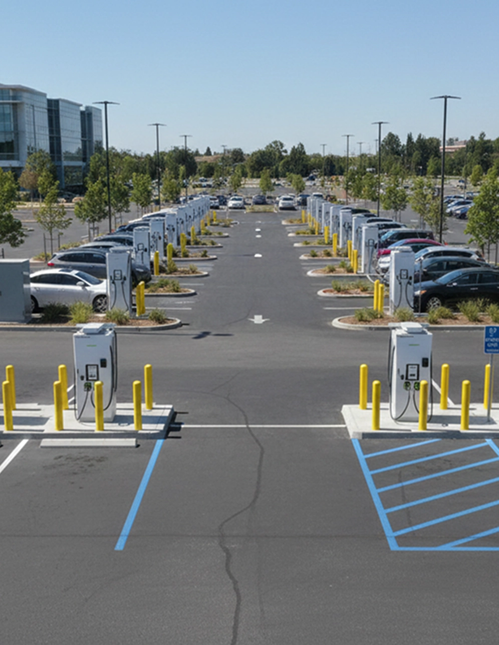 Electric vehicle charging station in a parking lot with rows of cars and chargers under clear sky.
