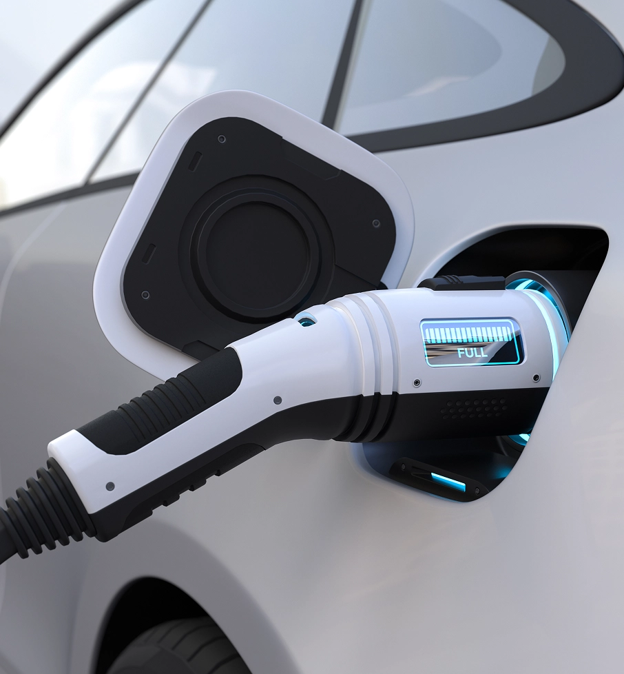 Electric car charging with a connector showing full battery status on a white vehicle.