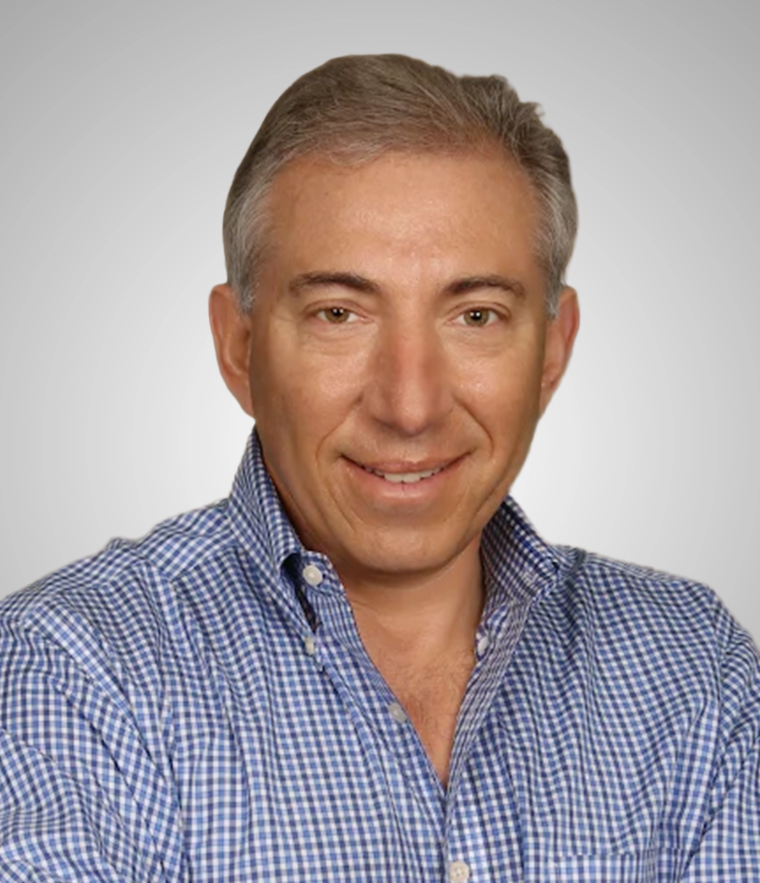 Middle-aged man with gray hair wearing a blue checkered shirt smiling against a light gray background.