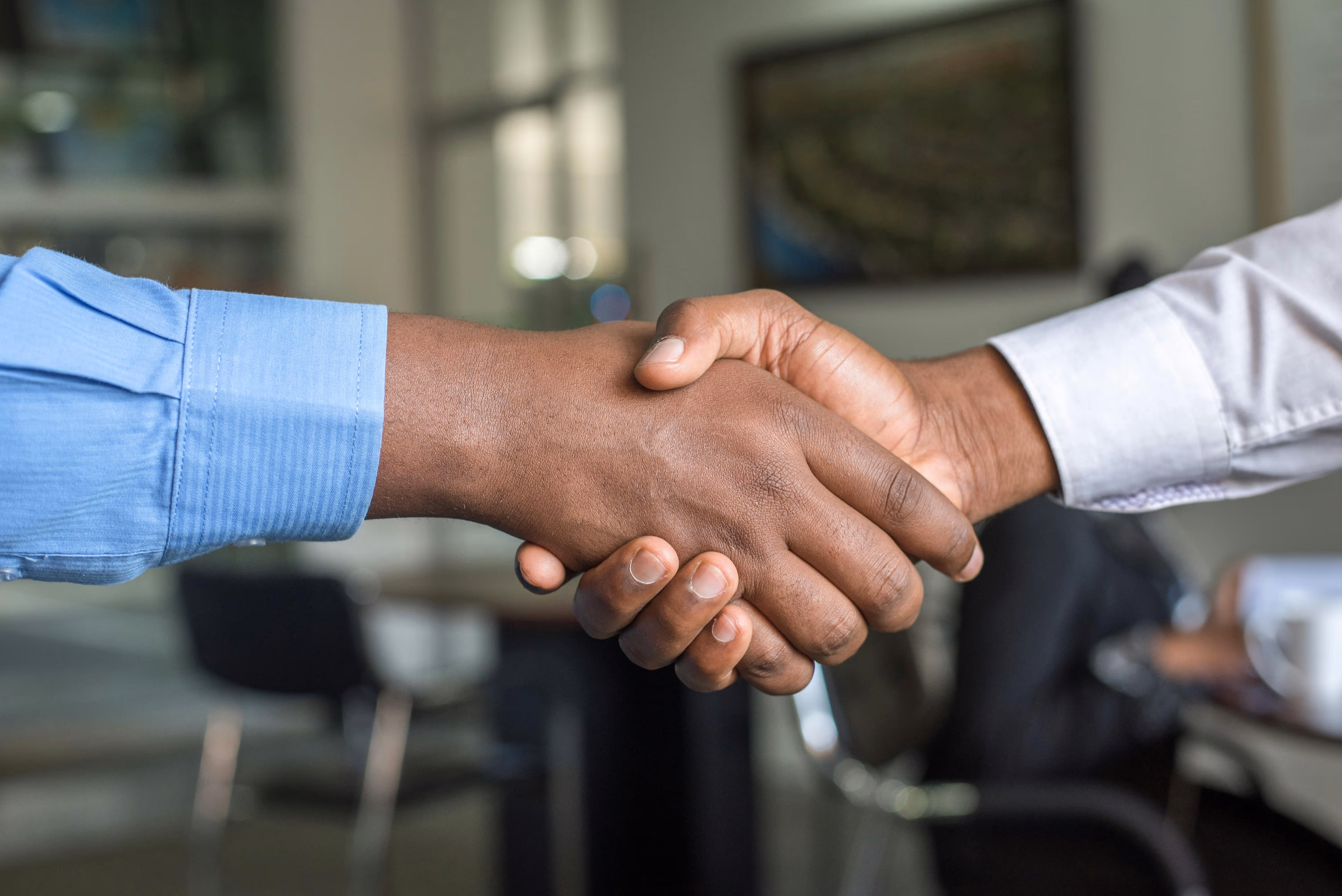 Close-up of two people shaking hands in a professional office setting.