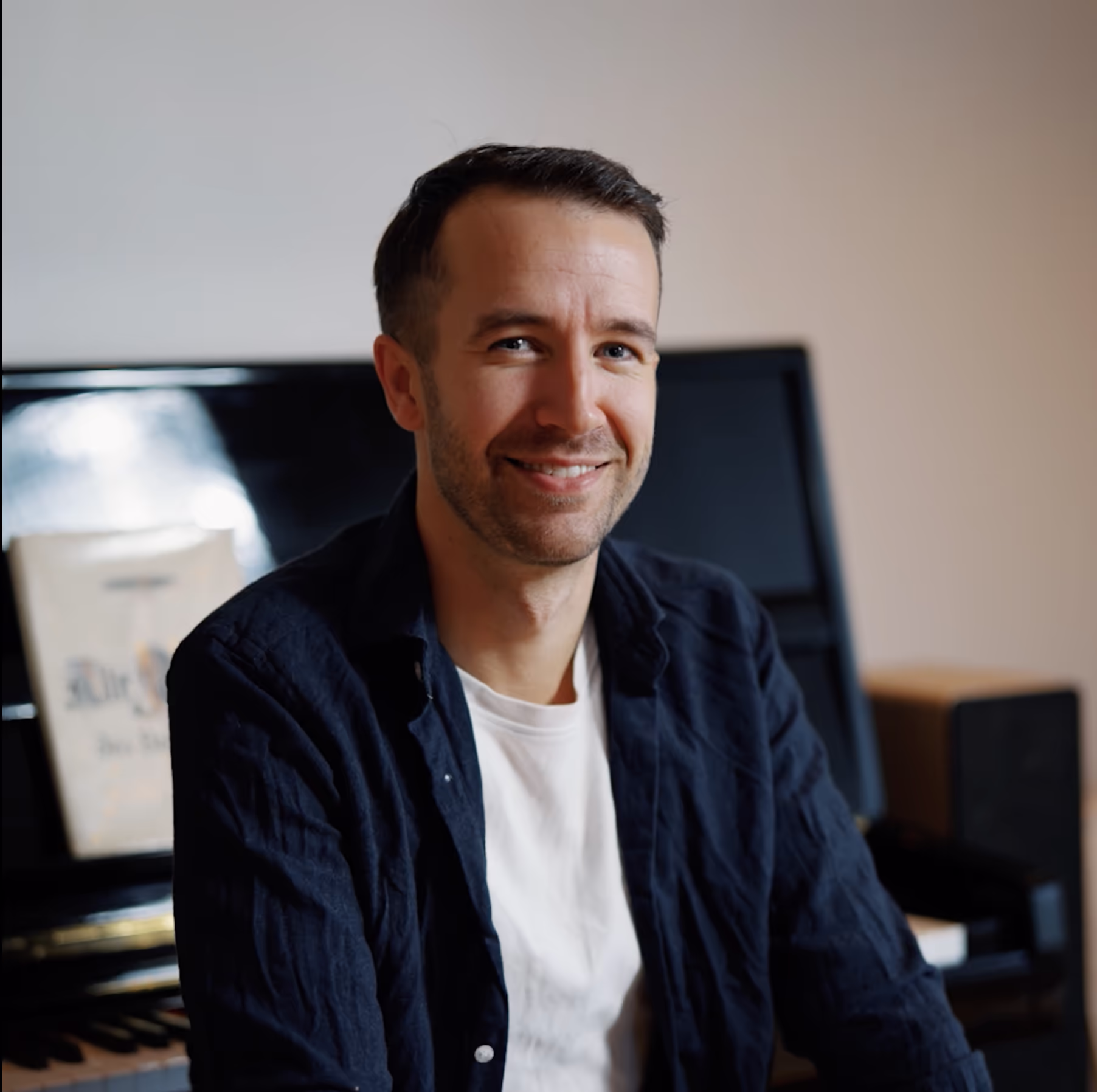 Pasient Emil Solli Tangen sitter her med pianoet sitt og smiler fornøyd etter synskorrigerende behandling hos OSLO SYN