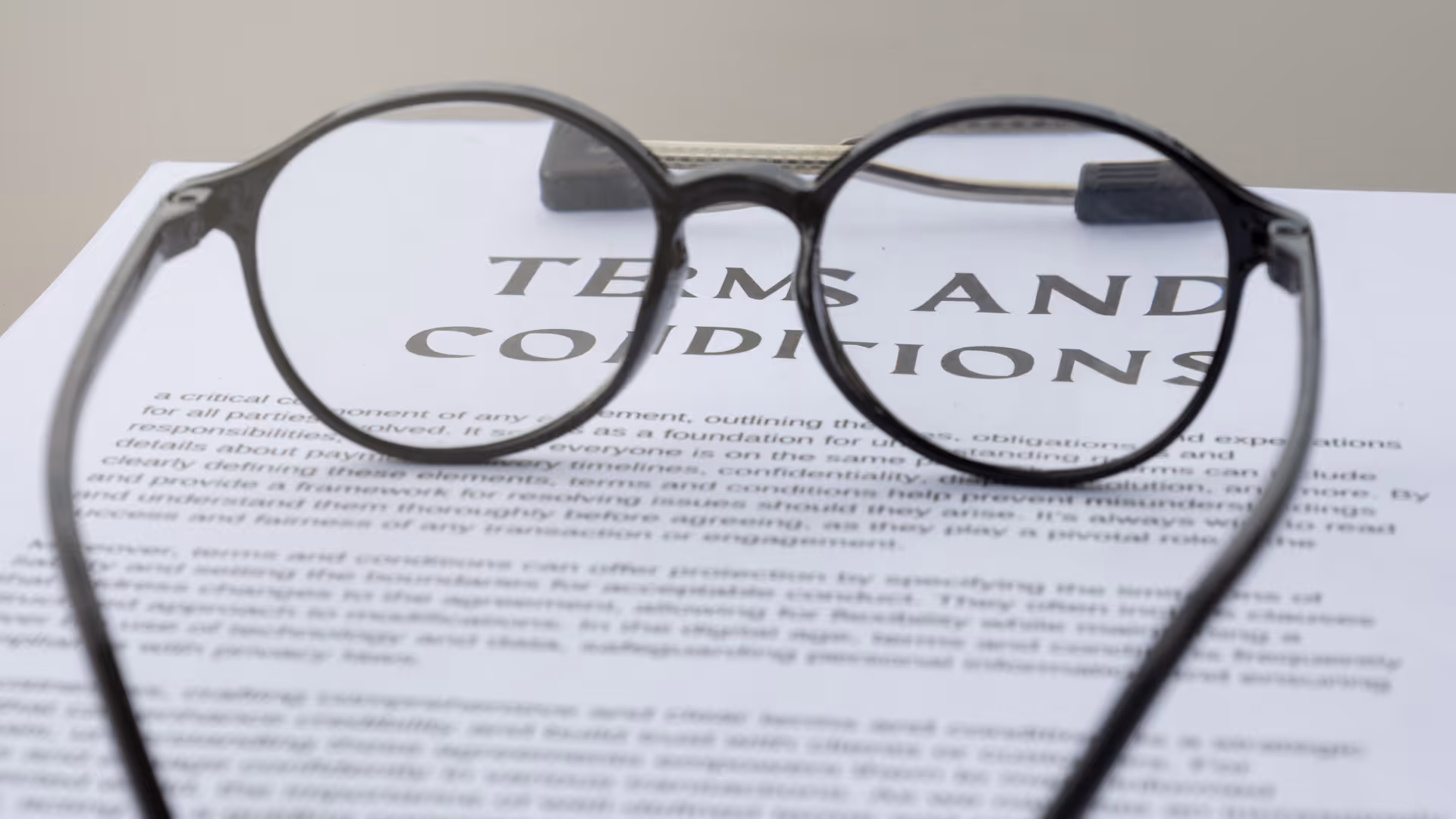 Black round eyeglasses resting on a paper titled Terms and Conditions.