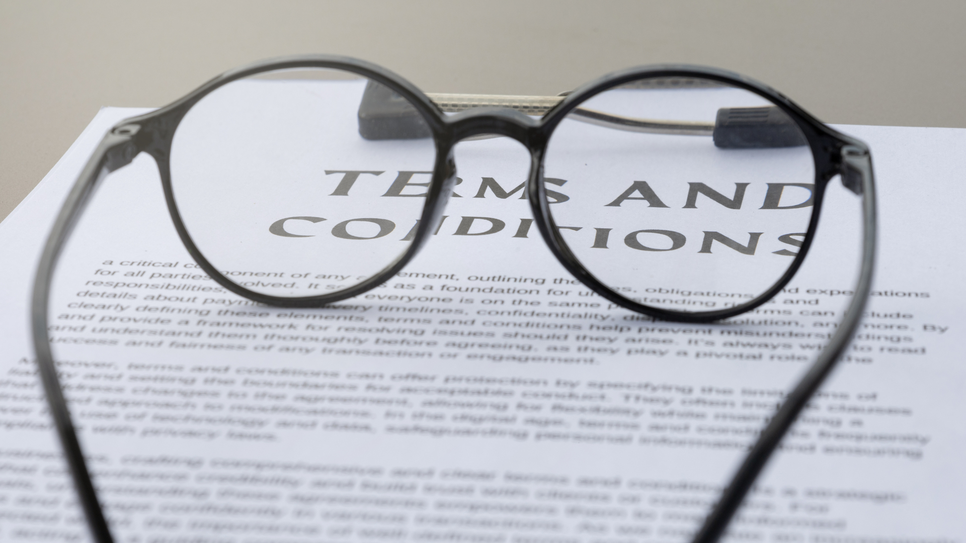 Black round eyeglasses resting on a paper titled Terms and Conditions.
