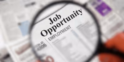 Magnifying glass focusing on newspaper text reading 'Job Opportunity Employment'.