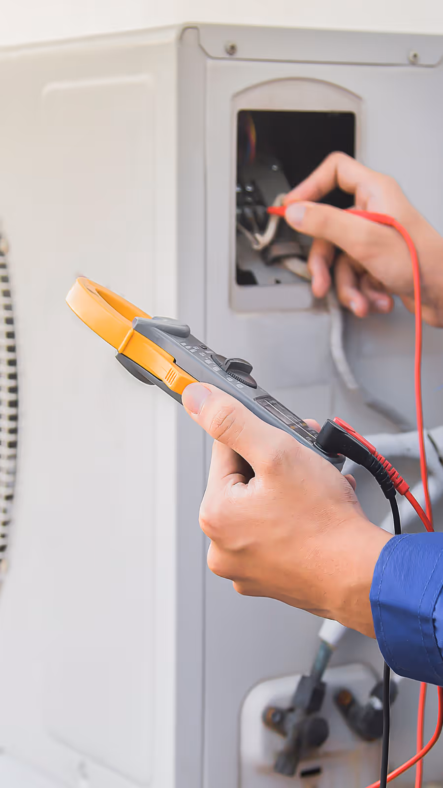 Technician using a multimeter to check electrical connections inside an HVAC unit.
