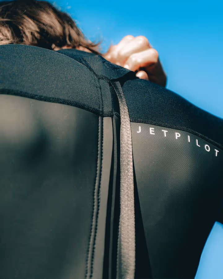 Person wearing a black wetsuit with the brand name JETPILOT visible on the shoulder.