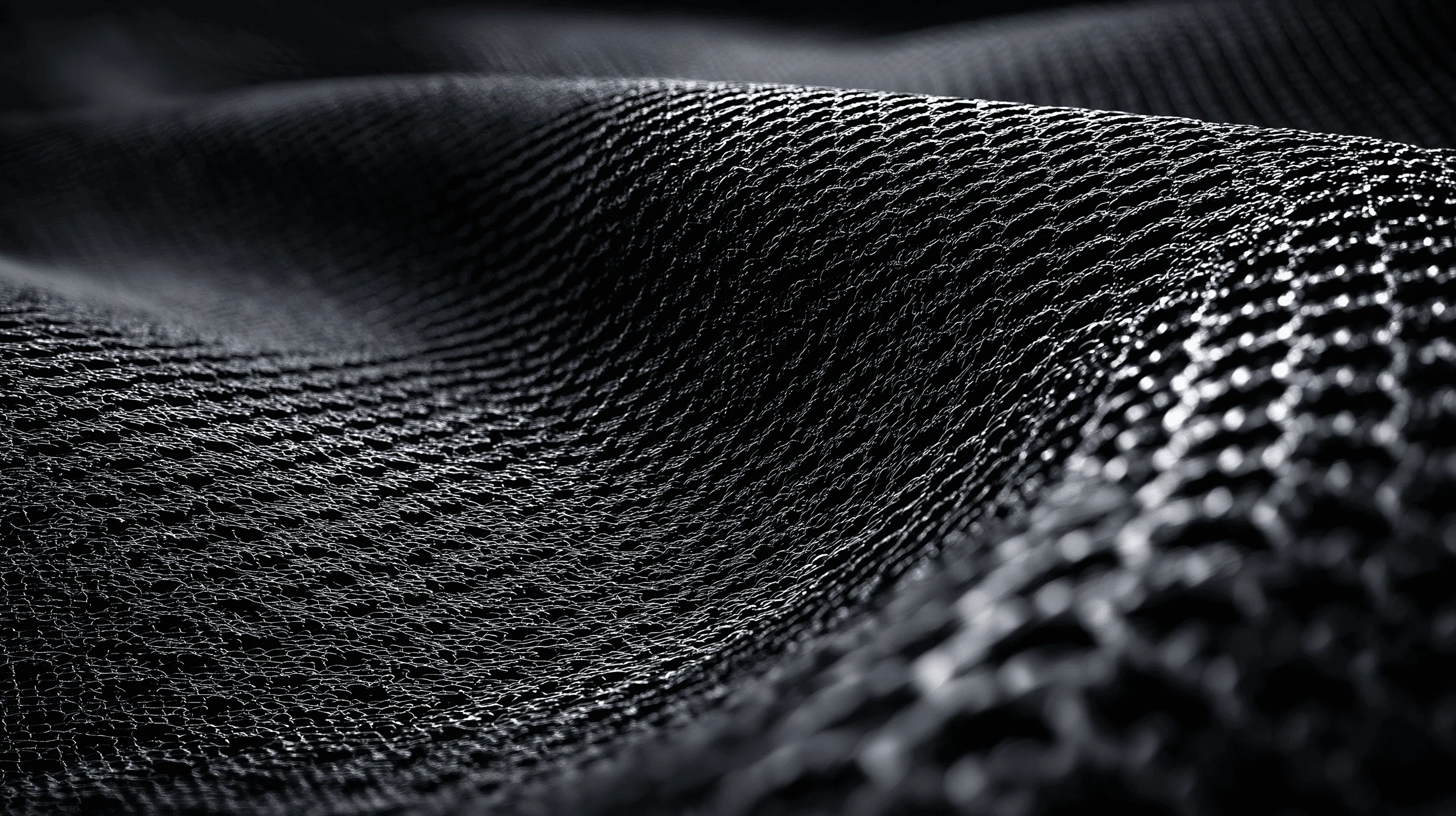 Close-up of a textured black fabric with a wavy pattern and intricate mesh-like surface.