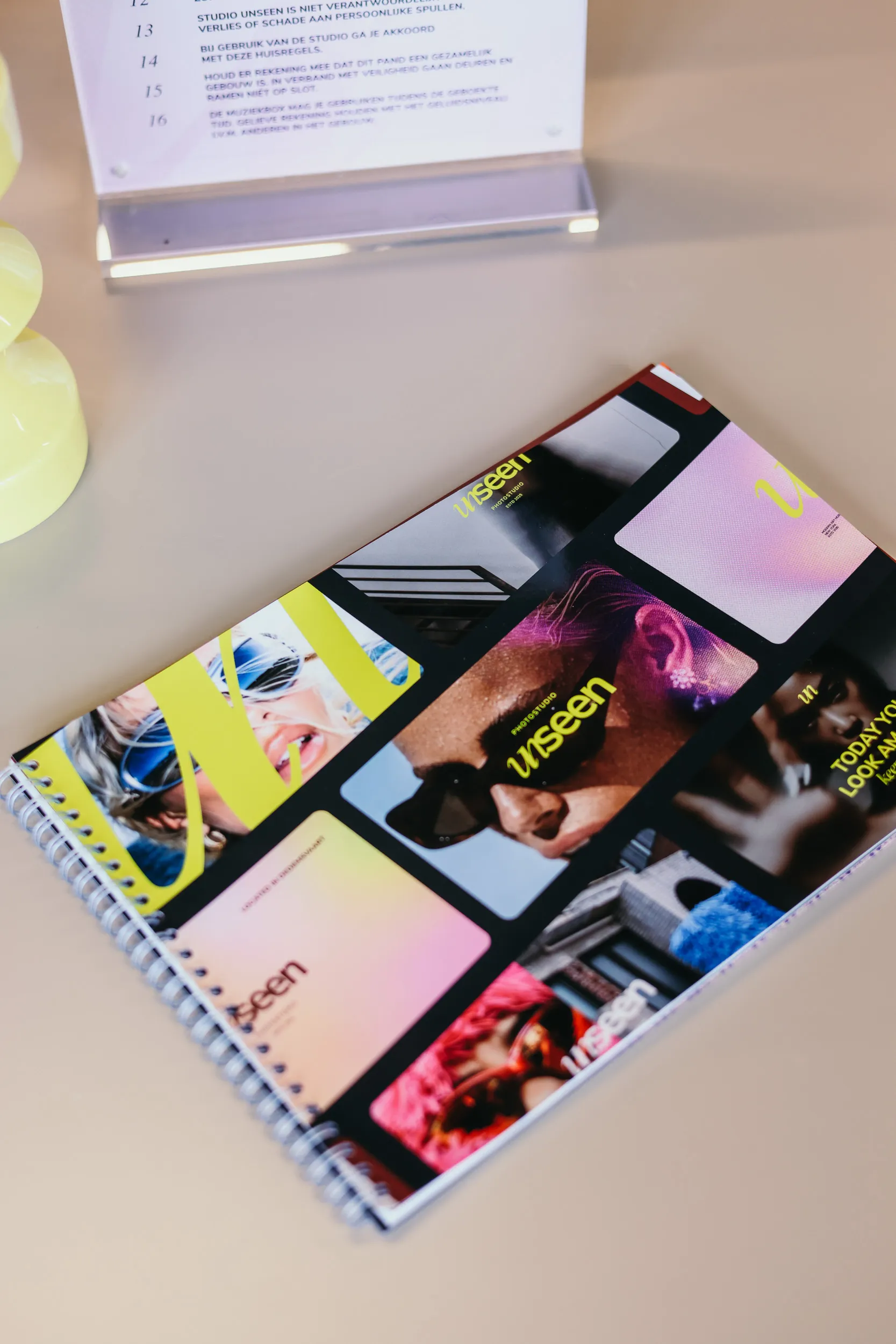 Spiraalgebonden notitieboekje met kleurrijke foto’s en tekst 'unseen' op het tafelblad.
