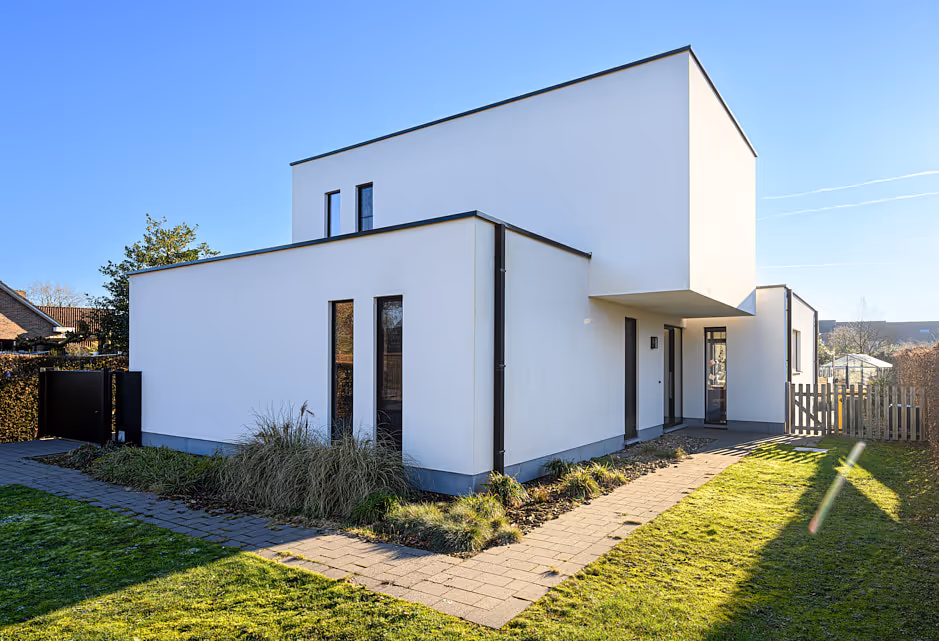 Kubistische witte nieuwbouwwoning met plat dak en tuinpad in een woonwijk