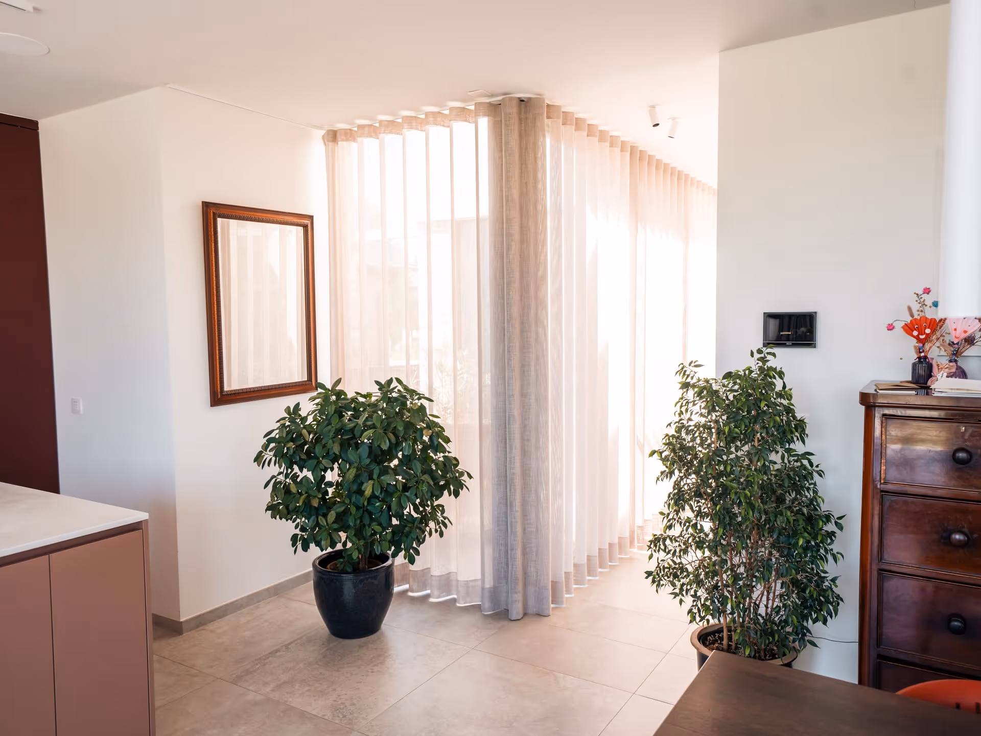 Lichtrijk interieur met vitrage, planten en houten kast waar interieurkeuzes samenkomen