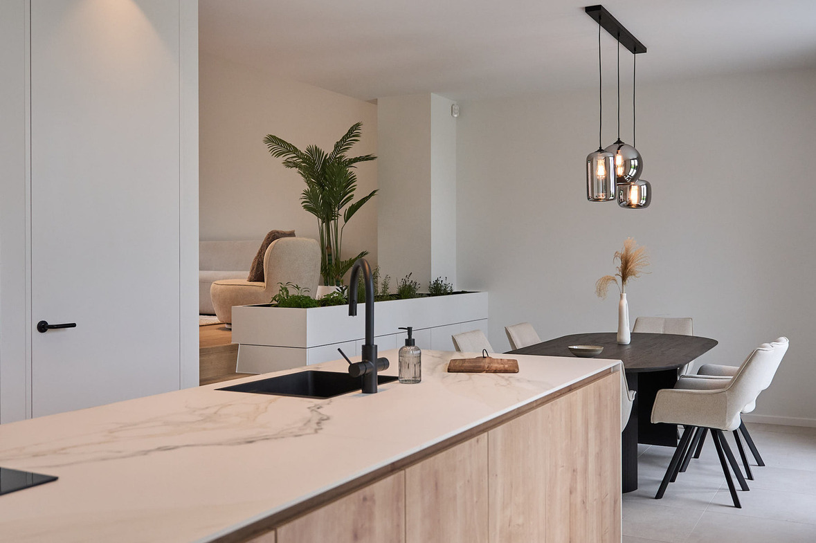 Strak gemoderniseerd interieur met keukeneiland in marmer en hout, eettafel en zithoek