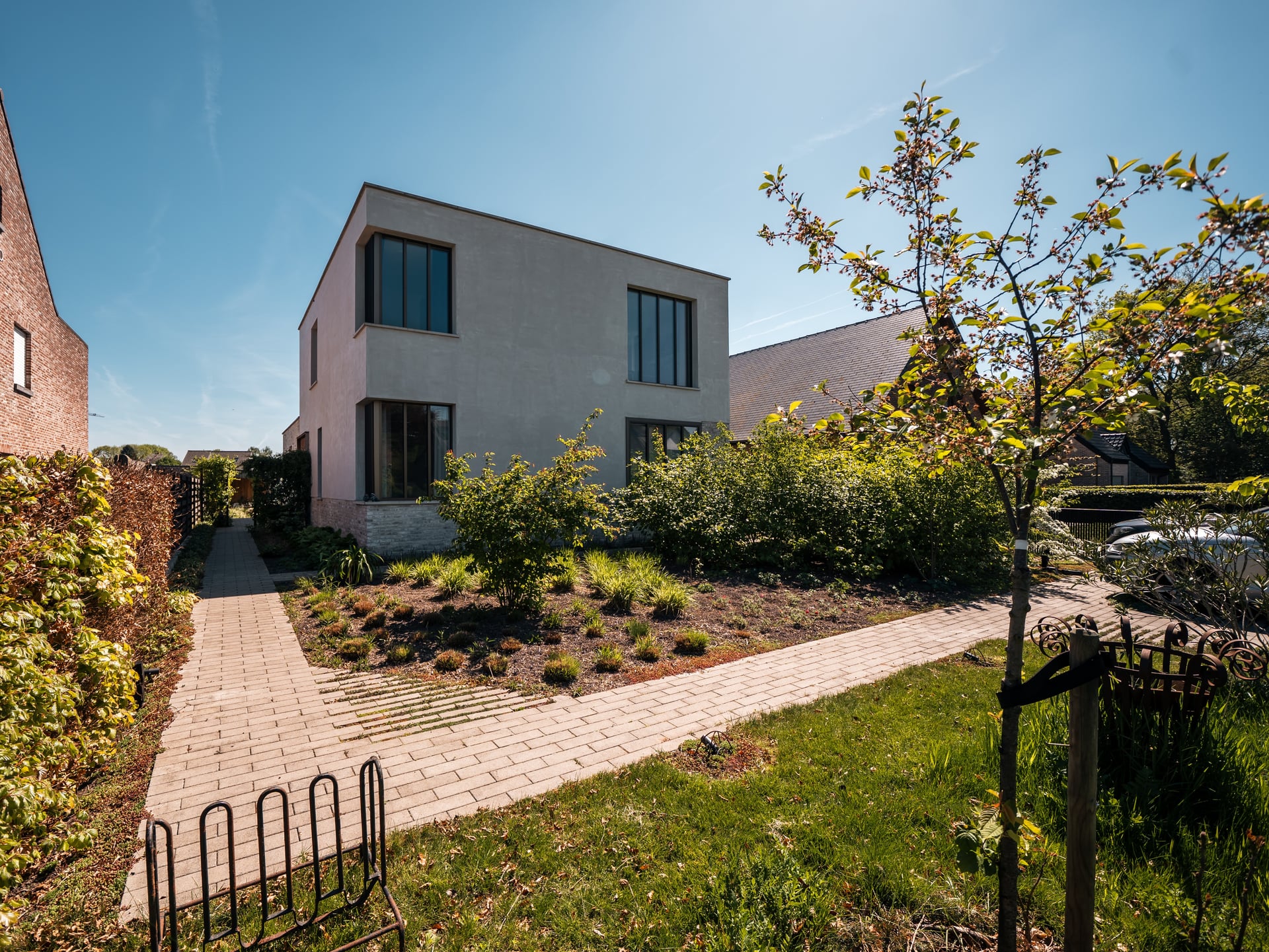 Moderne witte nieuwbouwwoning in houtskeletbouw met plat dak en aangelegde voortuin met borders