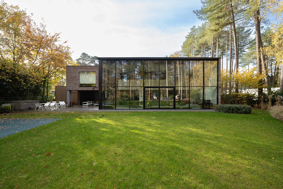 Tuinzijde met zwarte aluminium veranda over de volledige breedte en ruim gazon
