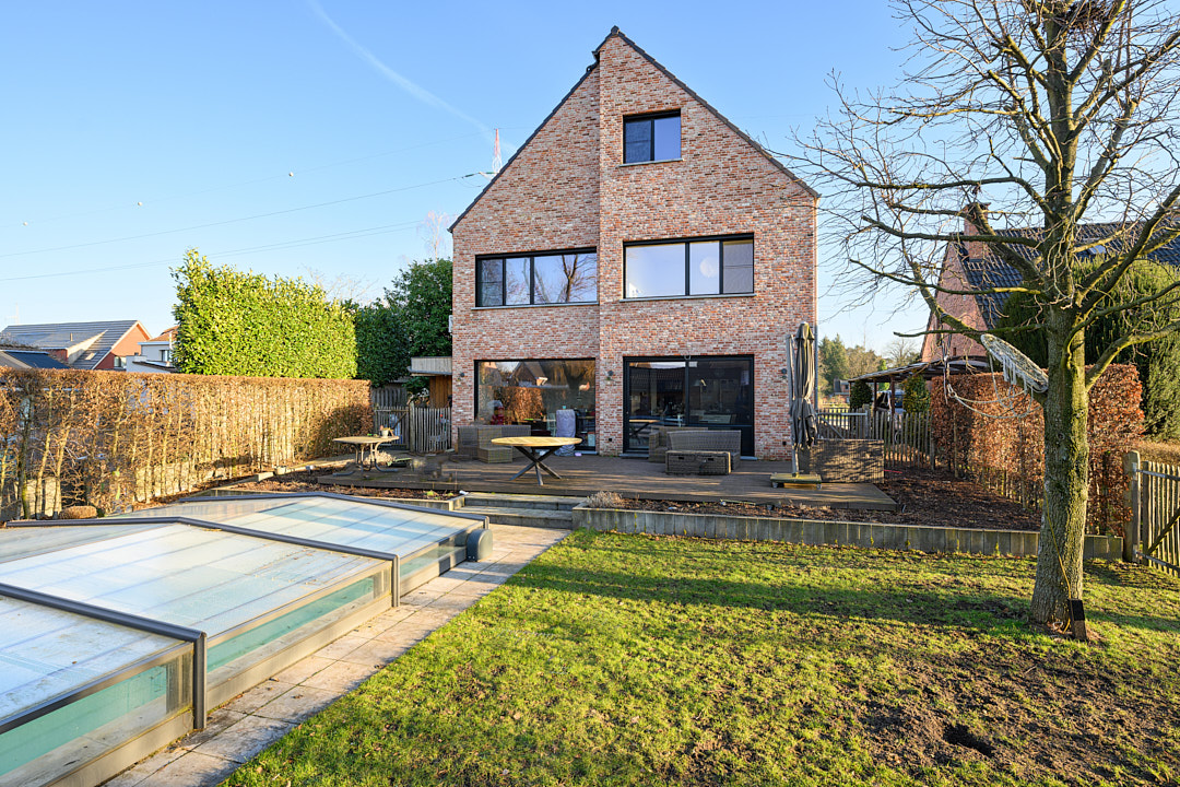 Achtergevel met terras, tuin en zwembad van de energiezuinig gerenoveerde woning