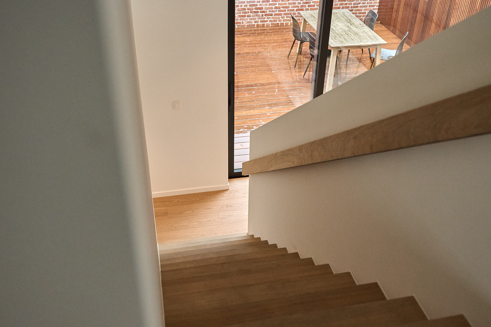 Houten trap met zicht op de eethoek en het terras door grote glaspartijen
