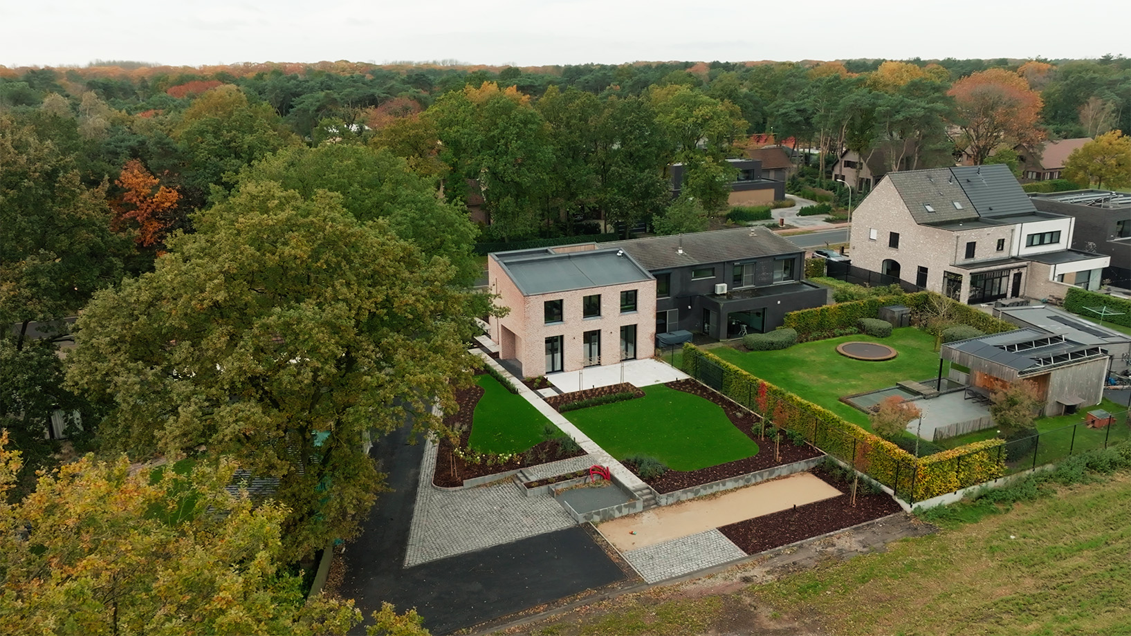 Luchtfoto van de woning in Merksplas met aangelegde tuin, oprit en omliggende bebouwing aan de bosrand