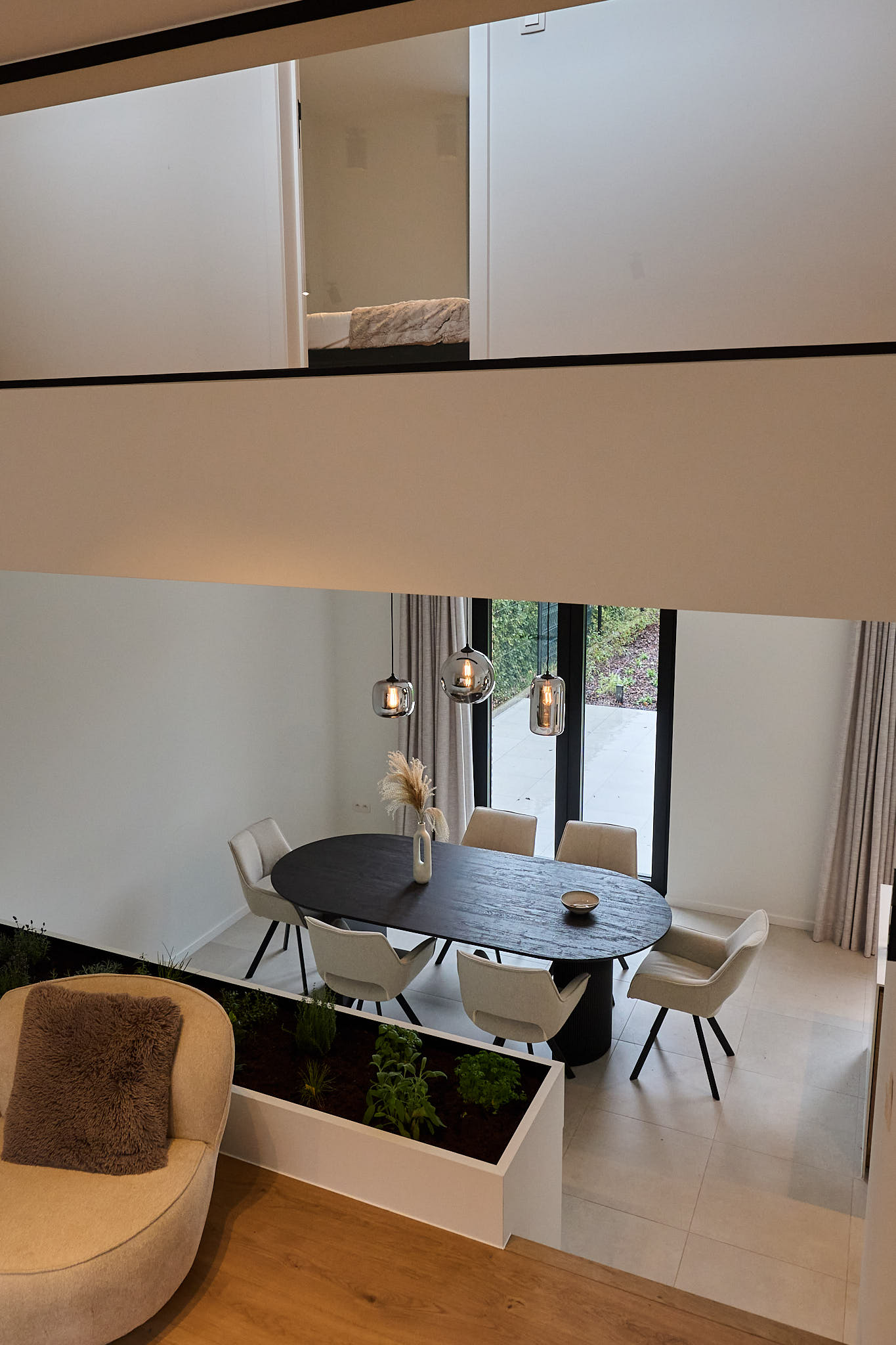 Dubbelhoge leefruimte met ovale eettafel, kruidenbak en vide met zicht op de bovenverdieping