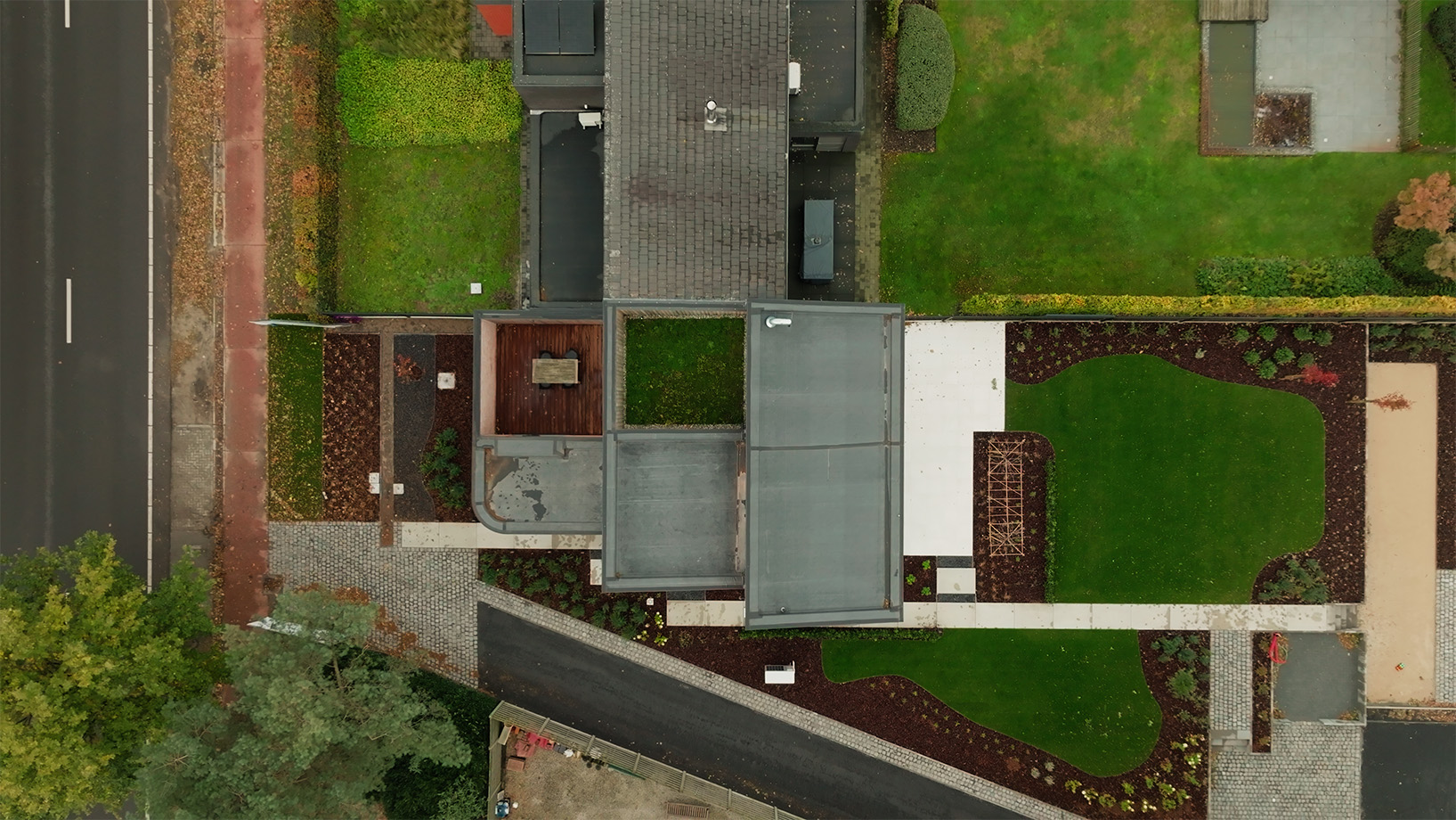 Achtergevel met ruime terrasdeuren, aangelegde tuin en pergola, van bovenaf gefotografeerd