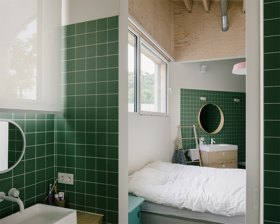 Badkamer met groene tegels, ingebouwd bad en houten plafond in zichtwerk