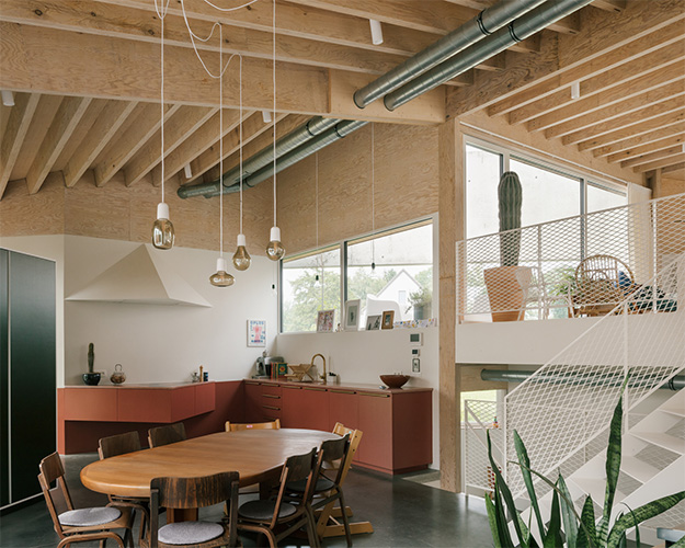 Open leefkeuken met zichtbare houten balken, terracotta keuken en witte wenteltrap