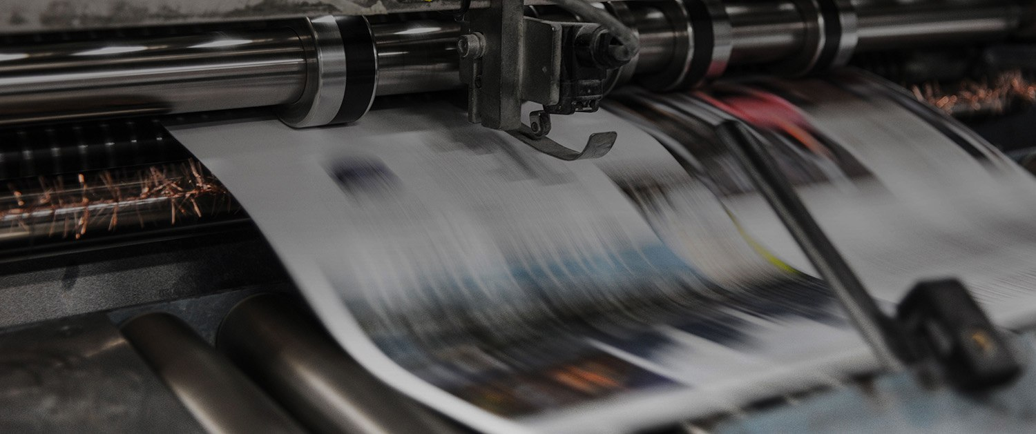 Close-up of a printing press producing blurred, fast-moving sheets of printed paper.