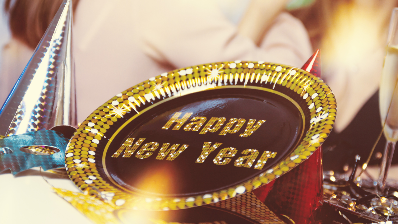 New Year's party hats, a metallic mask, streamers, and a Happy New Year plate