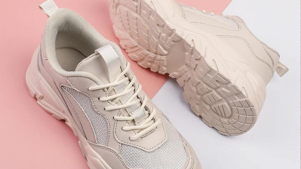 Pair of cream chunky sneakers on a pink and white background