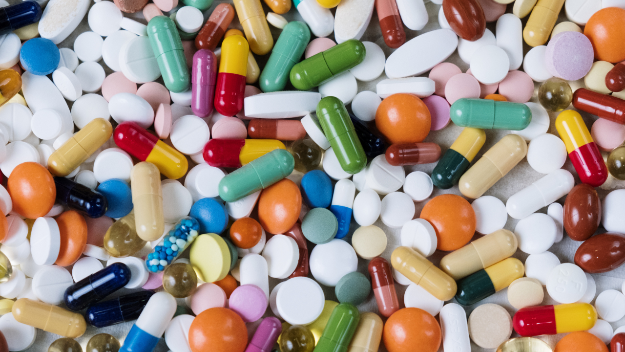 Assorted tablets and capsules spread across a white surface