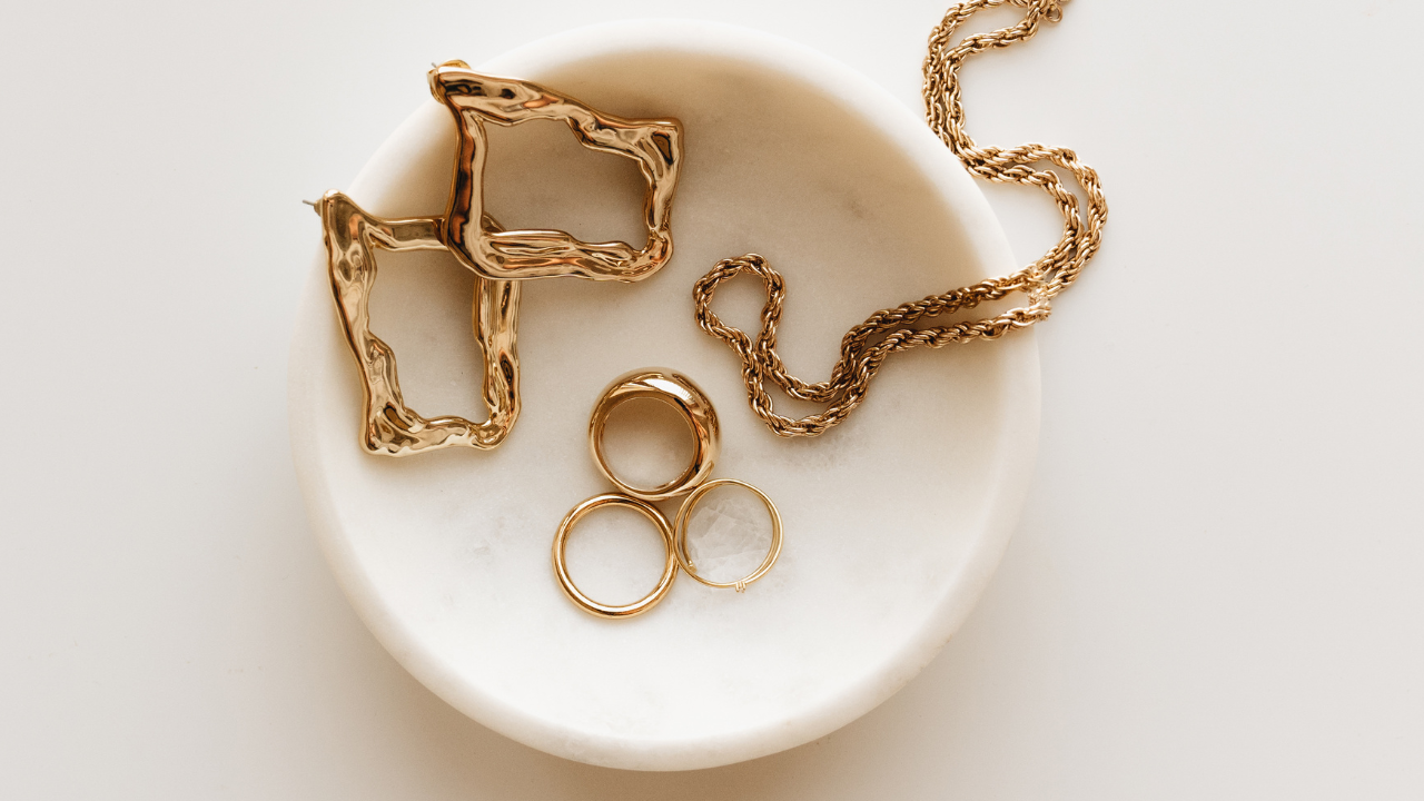 Gold necklaces and rings arranged in a white dish