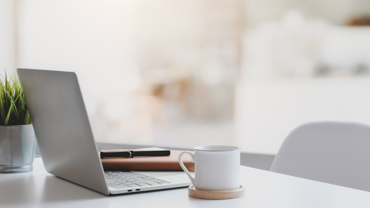 A laptop and coffee cup on a clean home-office desk